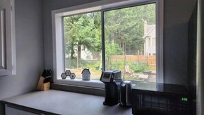 A kitchen with a large window, a coffee maker, and a toaster on the counter.
