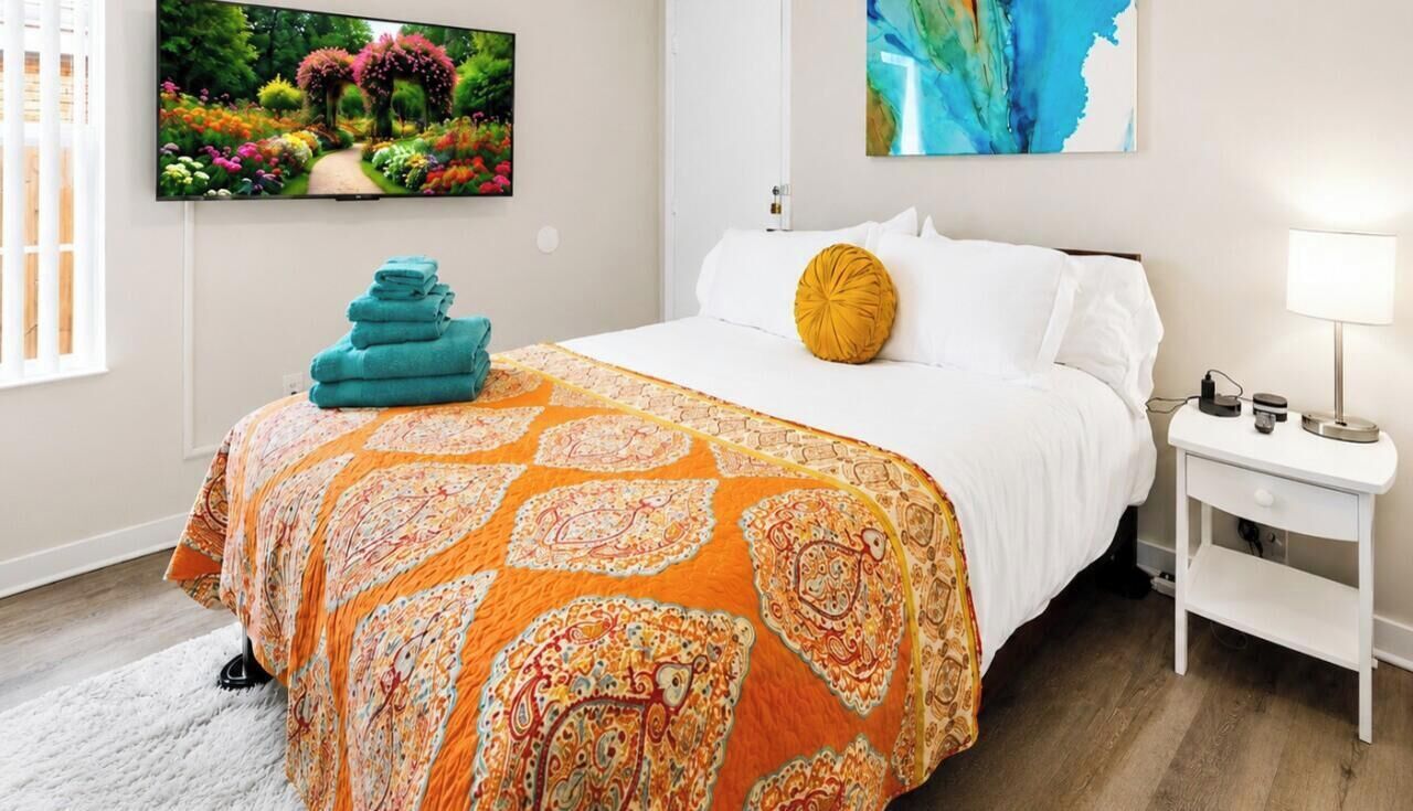 Une chambre d’hôtel avec un lit, une télévision, une table de chevet et un tableau au mur.