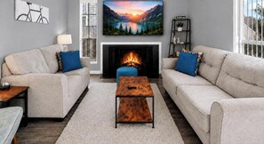 A living room with a fireplace, two sofas, a coffee table, and a large painting above the fireplace.