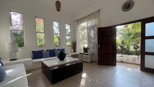 A modern living room with a sofa, coffee table, and large windows.