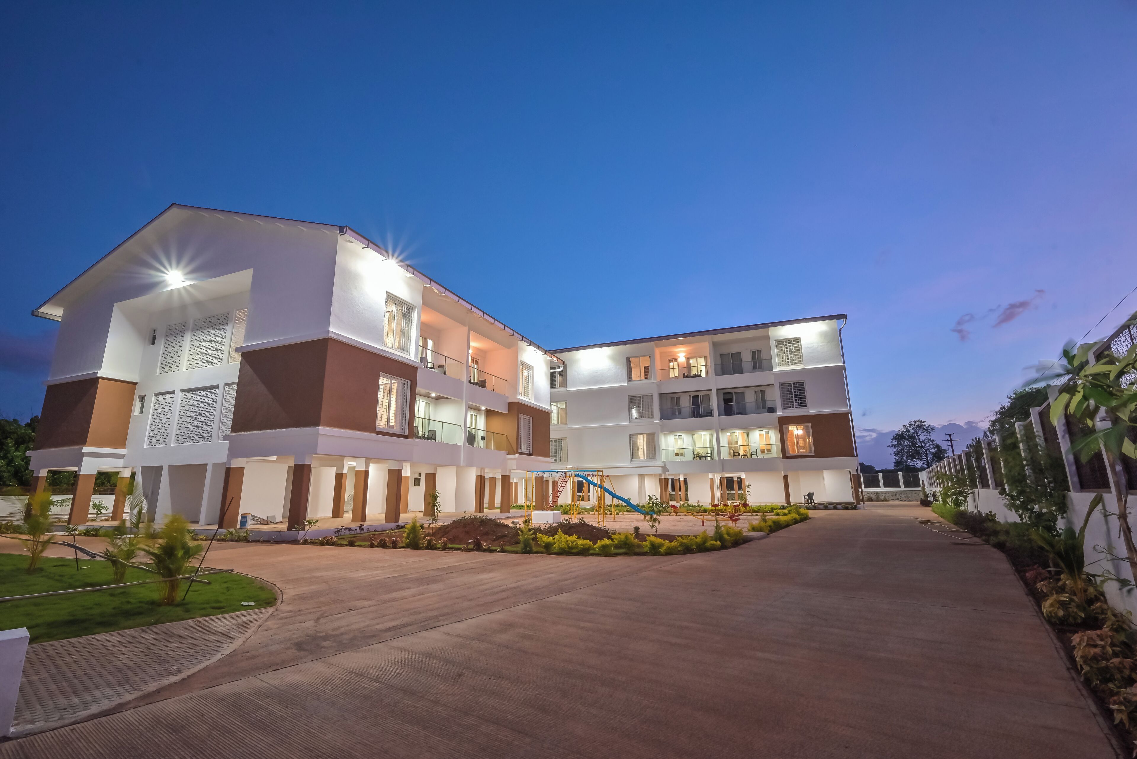 A multi-story hotel with a central courtyard, balconies, and a well-lit entrance.