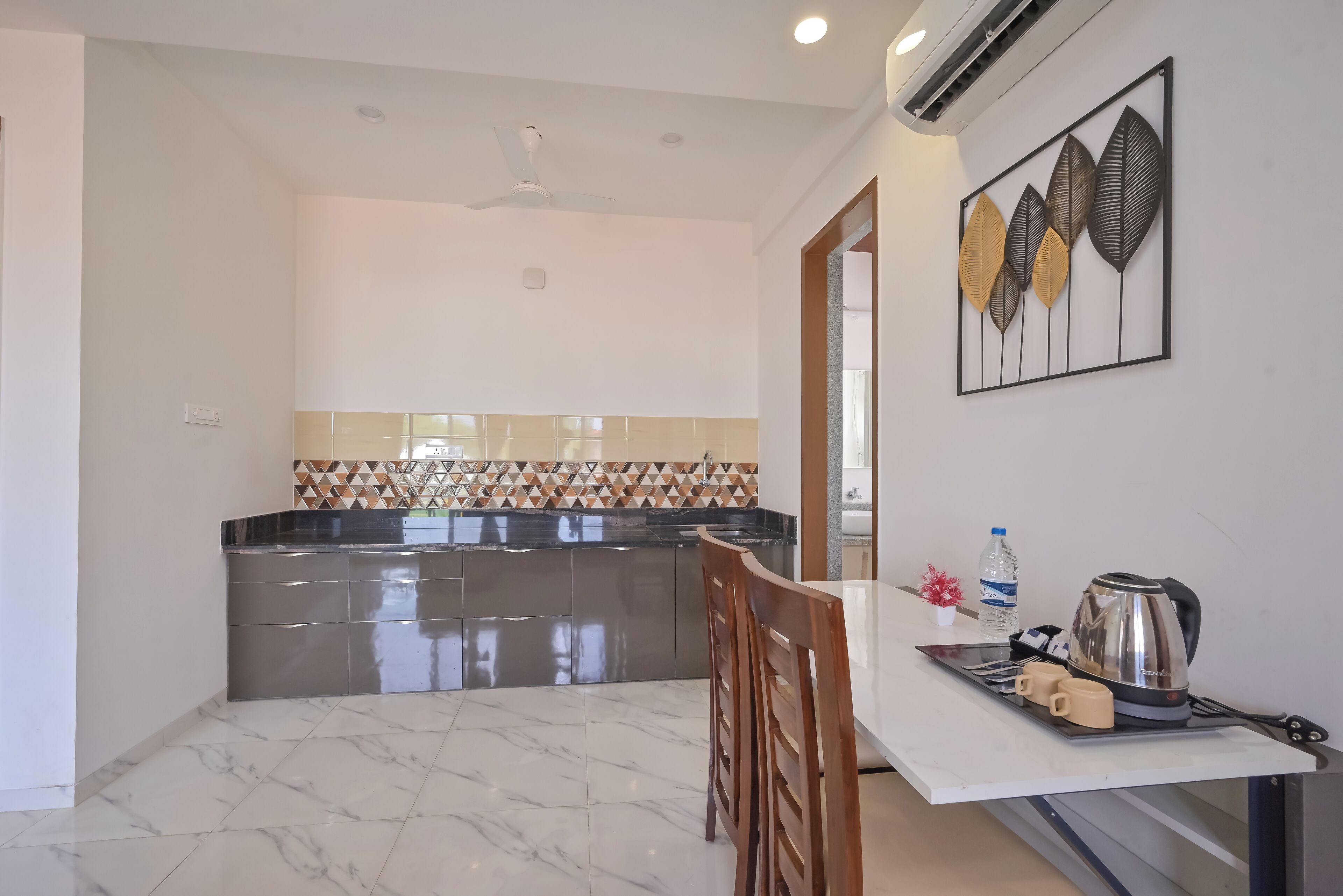 A modern kitchen with a marble floor, a stainless steel countertop, and a dining area with a table and chairs.
