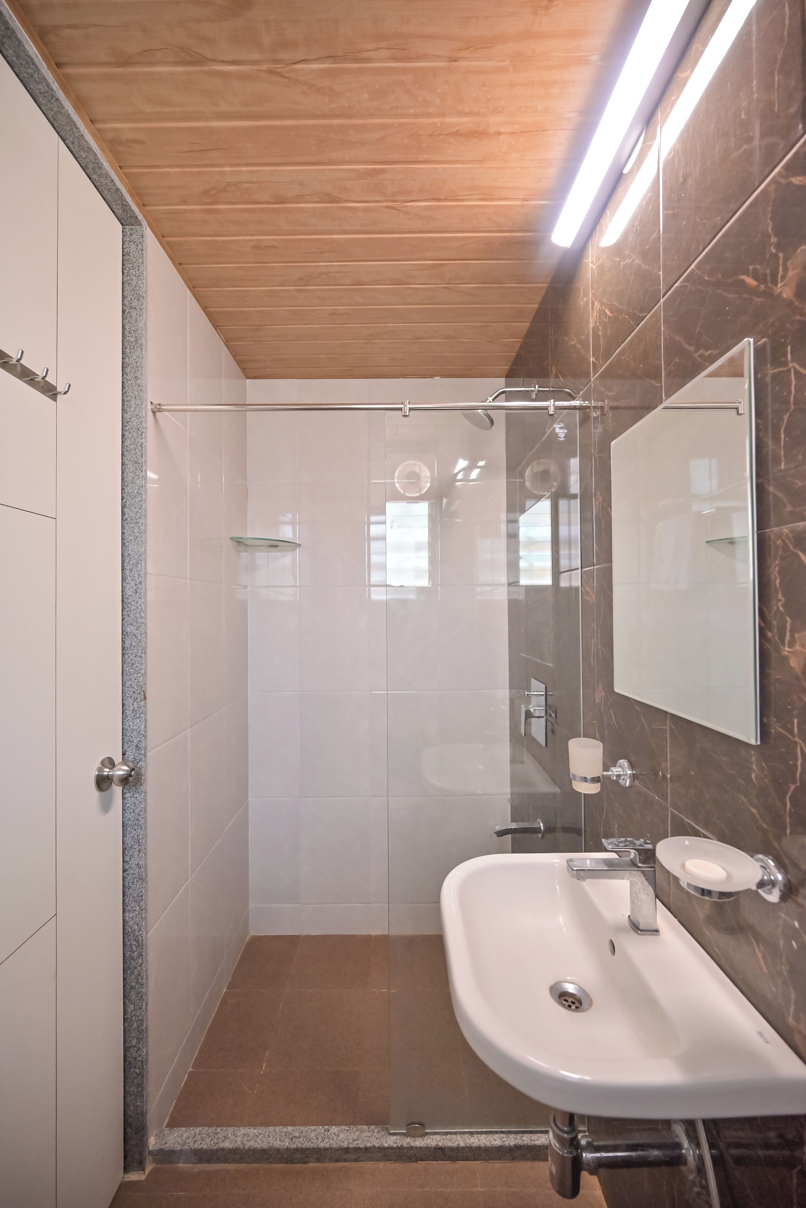 Un baño moderno con ducha, lavamanos y espejo.