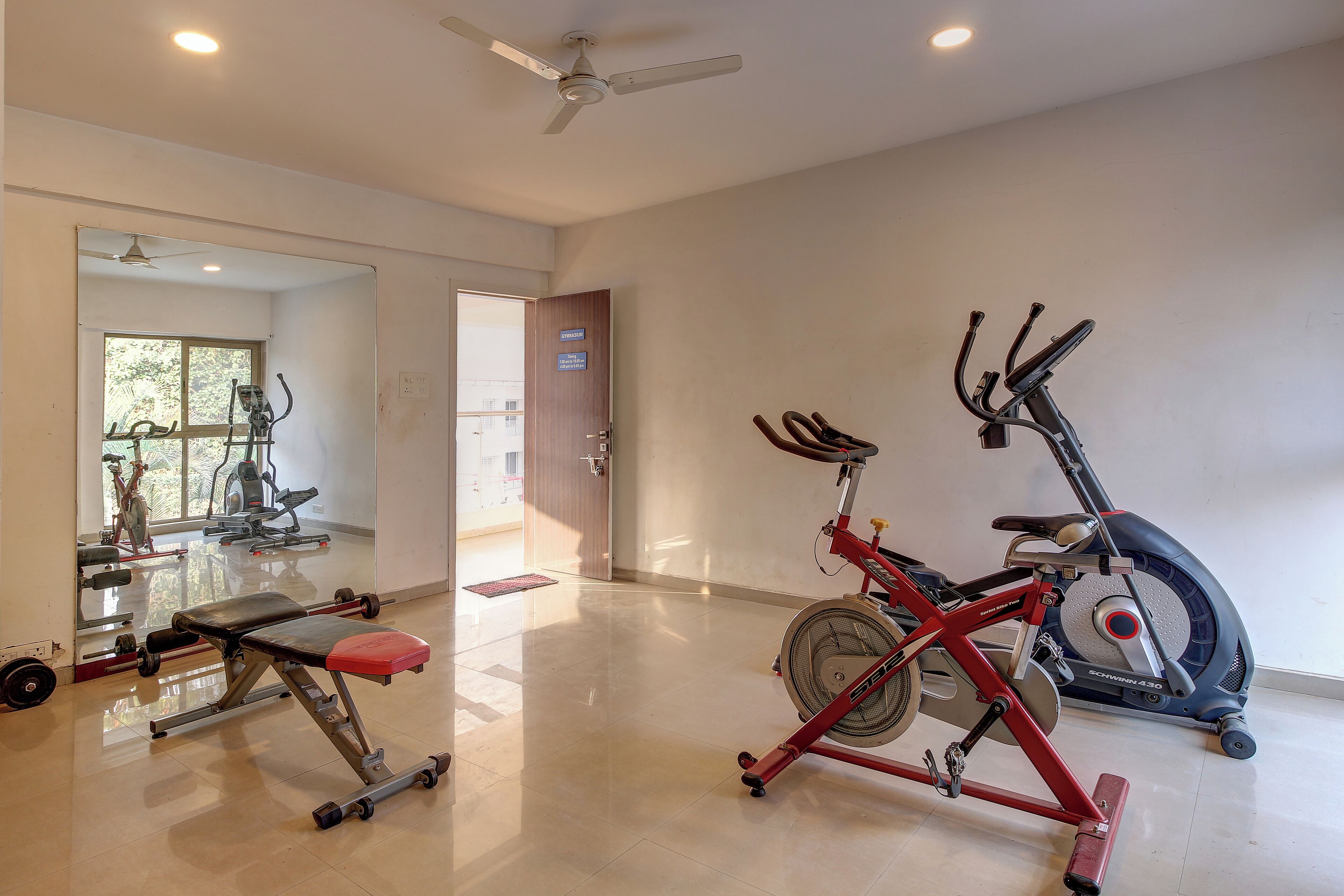 A gym with exercise equipment, including a bench, a stationary bike, and a rowing machine.