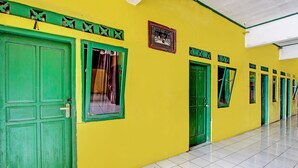 A hallway with green doors and yellow walls, leading to individual rooms.
