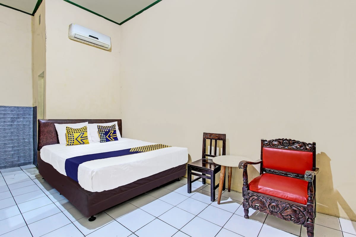 A bedroom with a bed, a chair, and an air conditioning unit.