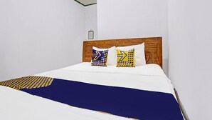 A neatly made bed with a wooden headboard, two pillows with geometric patterns, and a blue and yellow blanket.