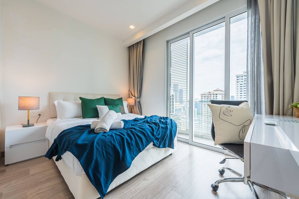 Een moderne hotelkamer met een groot bed, een bureau en uitzicht op de stad.