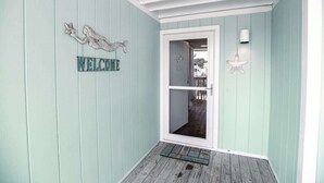 Una habitación con paredes azul claro, una puerta de madera y un cartel de bienvenida.