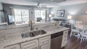 Una cocina con una isla grande, lavavajillas y un comedor con mesa y sillas.