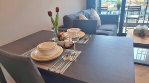 A dining table set with plates, bowls, and cutlery, a vase with flowers, and a glass of water. - B303- 1 Bedroom Condo With Sea View, Ao Nang Beach (Krabi)