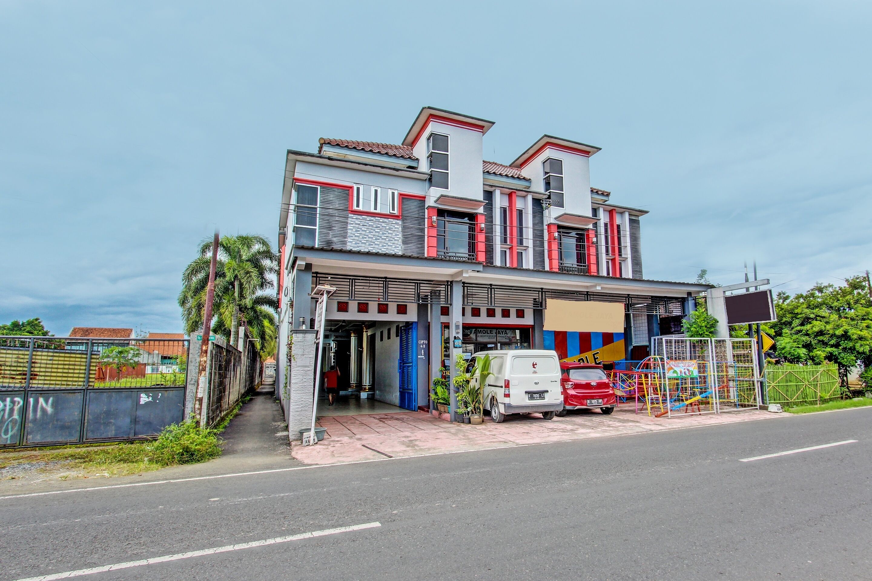 A two-story building with a garage entrance, a white van parked in front, and a playground with colorful equipment.