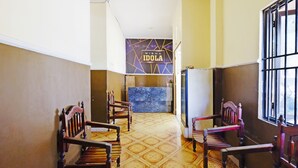 Un pasillo con sillas de madera, un mostrador de recepción y una pared de mármol con el texto "WISMA IDOLA".