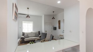 Un salon moderne avec un canapé, des fauteuils, une table basse en verre et des luminaires suspendus.