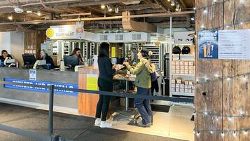 Mostrador de alquiler de equipo con un cartel de servicios de alquiler, una estación de computadoras y una exhibición de equipamiento para esquiar.
