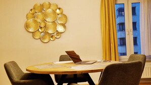 Une table ronde en bois, accompagnée de quatre chaises, d’un ordinateur portable et d’un élément décoratif mural.