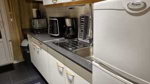 Une cuisine compacte équipée d’un réfrigérateur Whirlpool, d’une machine à café, d’un grille-pain et d’un évier.