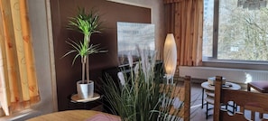 A room with a potted plant, a lamp, a chair, and a table.