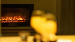 Une pièce avec une cheminée, une étagère remplie de bouteilles et un objet flou au premier plan.