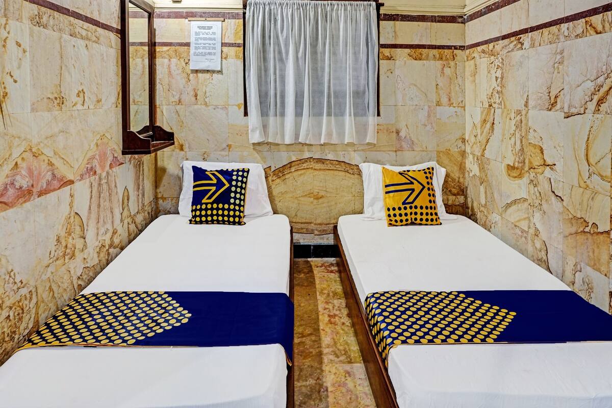 A room with two beds, each with a blue and yellow patterned bedspread, white pillows, and a wooden headboard.