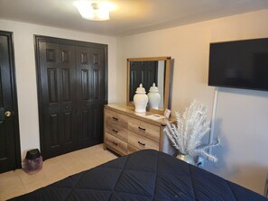 Un dormitorio con cama, cómoda, espejo y televisor.