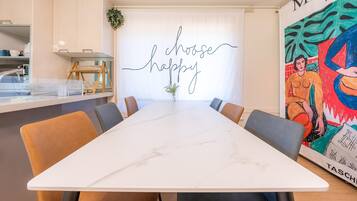 A conference room with a long table, chairs, a decorative sign, and a colorful painting.