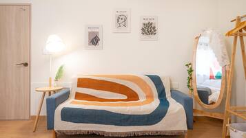 Una habitación con un sofá, una lámpara, un espejo y tres cuadros en la pared.