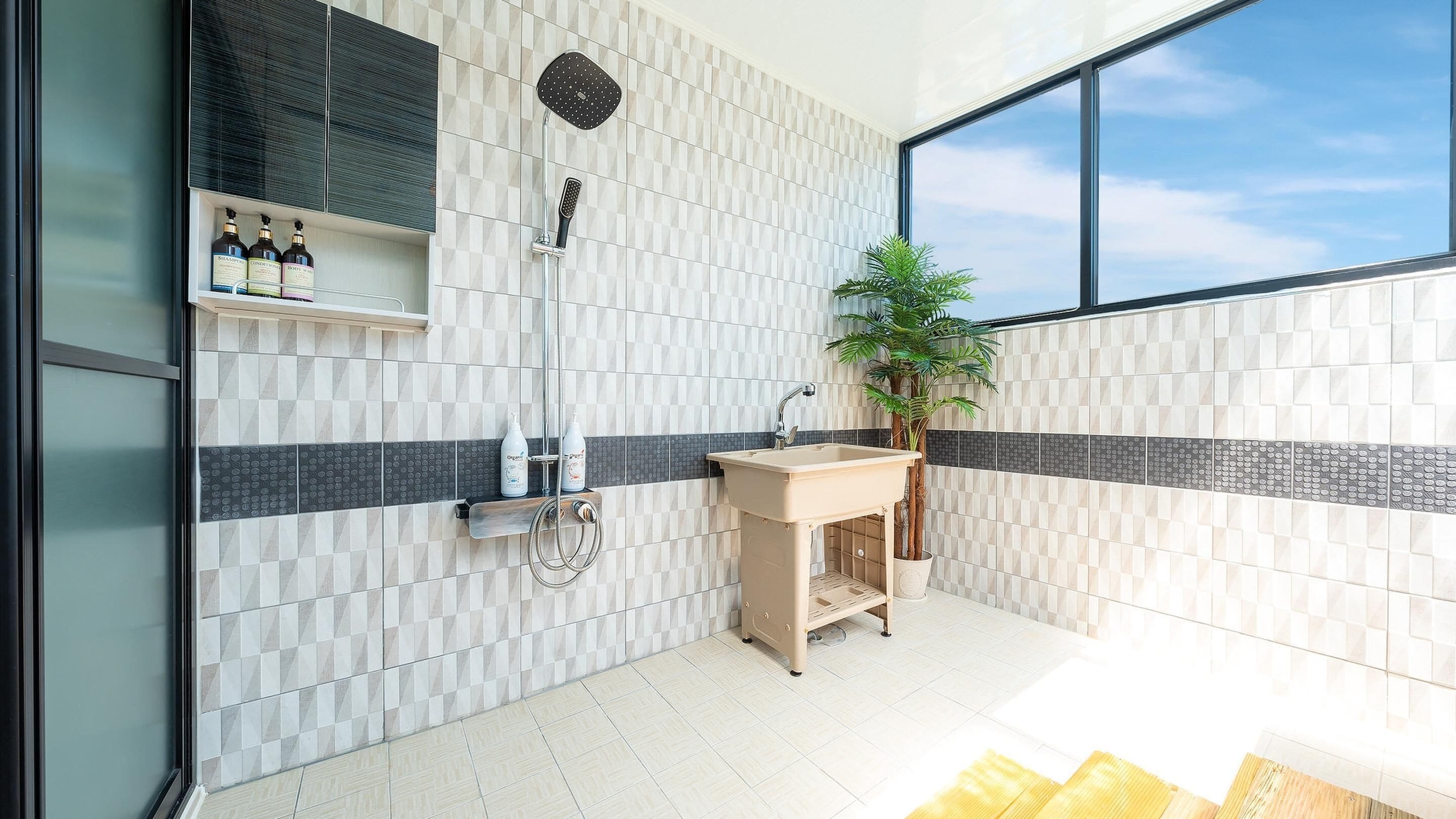 Une salle de bain moderne avec une douche, un lavabo et une plante en pot.