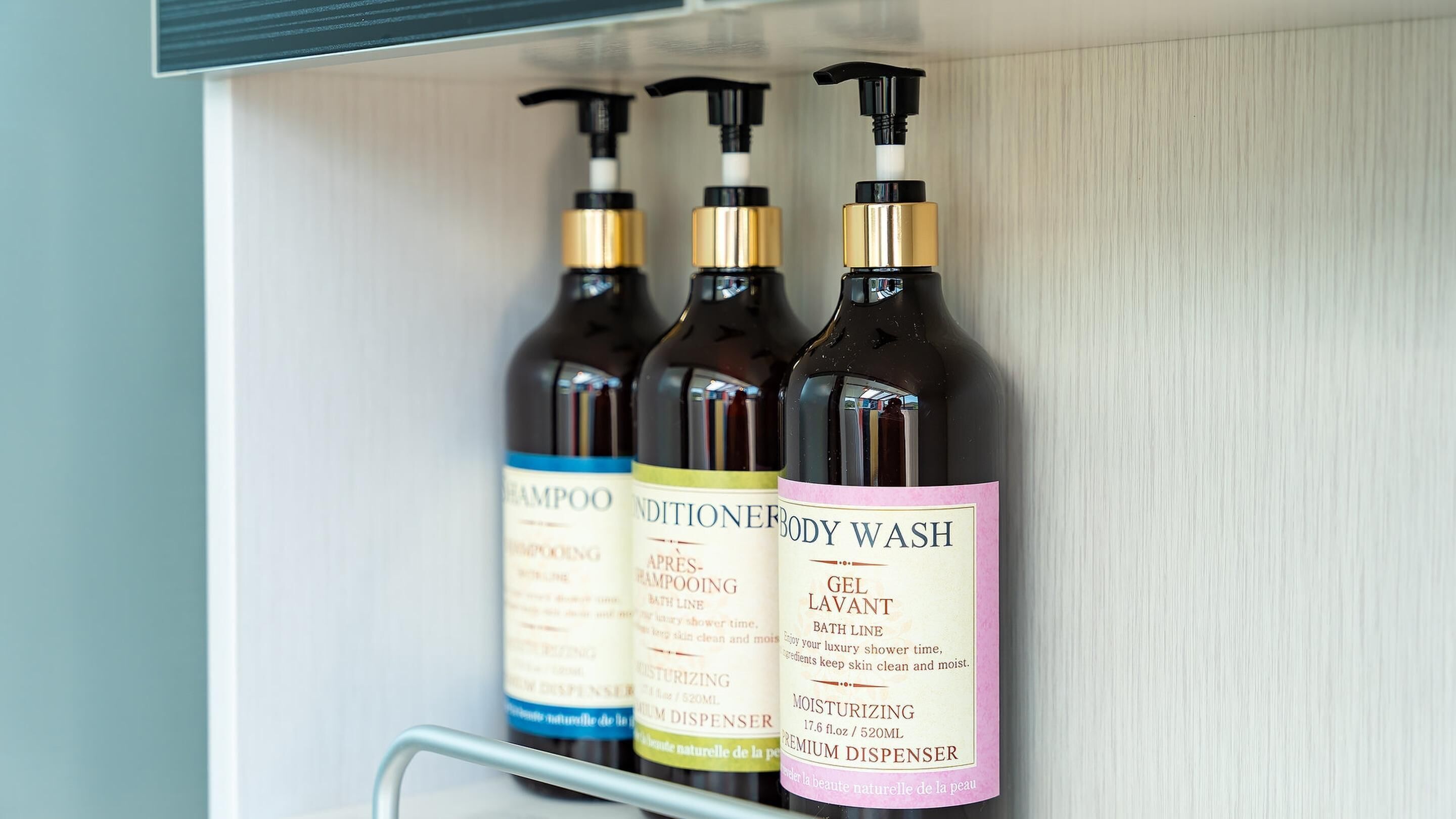 A shelf with three bottles of body wash and conditioner.
