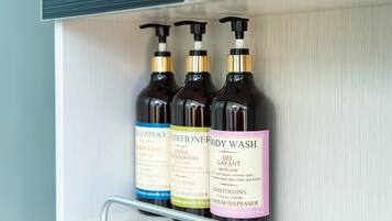 A shelf with three bottles of body wash and conditioner.
