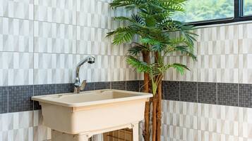 A bathroom with a sink, a mirror, and a potted plant.