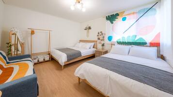 A room with two beds, a chair, a mirror, and a wall with a large abstract painting.