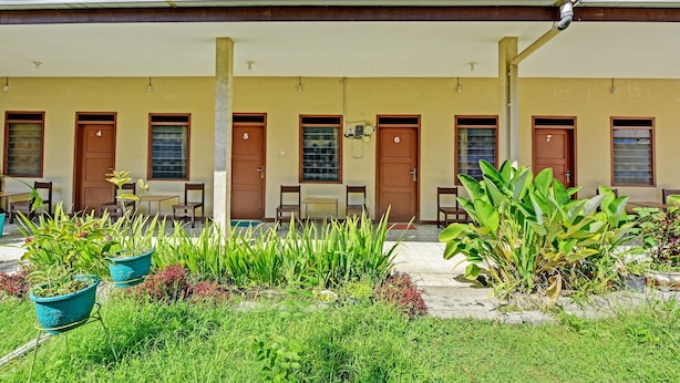 Un bâtiment dont les portes sont numérotées, doté d’une terrasse et agrémenté de plantes en pot.