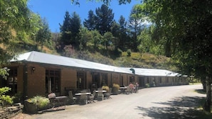 A rustic building with outdoor seating and a covered walkway. - Danseys Pass Hotel (Kyeburn Diggings)