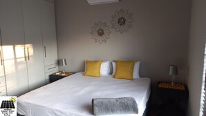 Une chambre d’hôtel avec un grand lit, deux tables de chevet, une armoire et des œuvres d’art décoratives au mur.