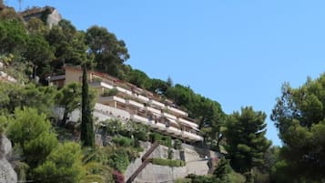 Un edificio en una ladera con varios balcones, rodeado de abundante vegetación y árboles.