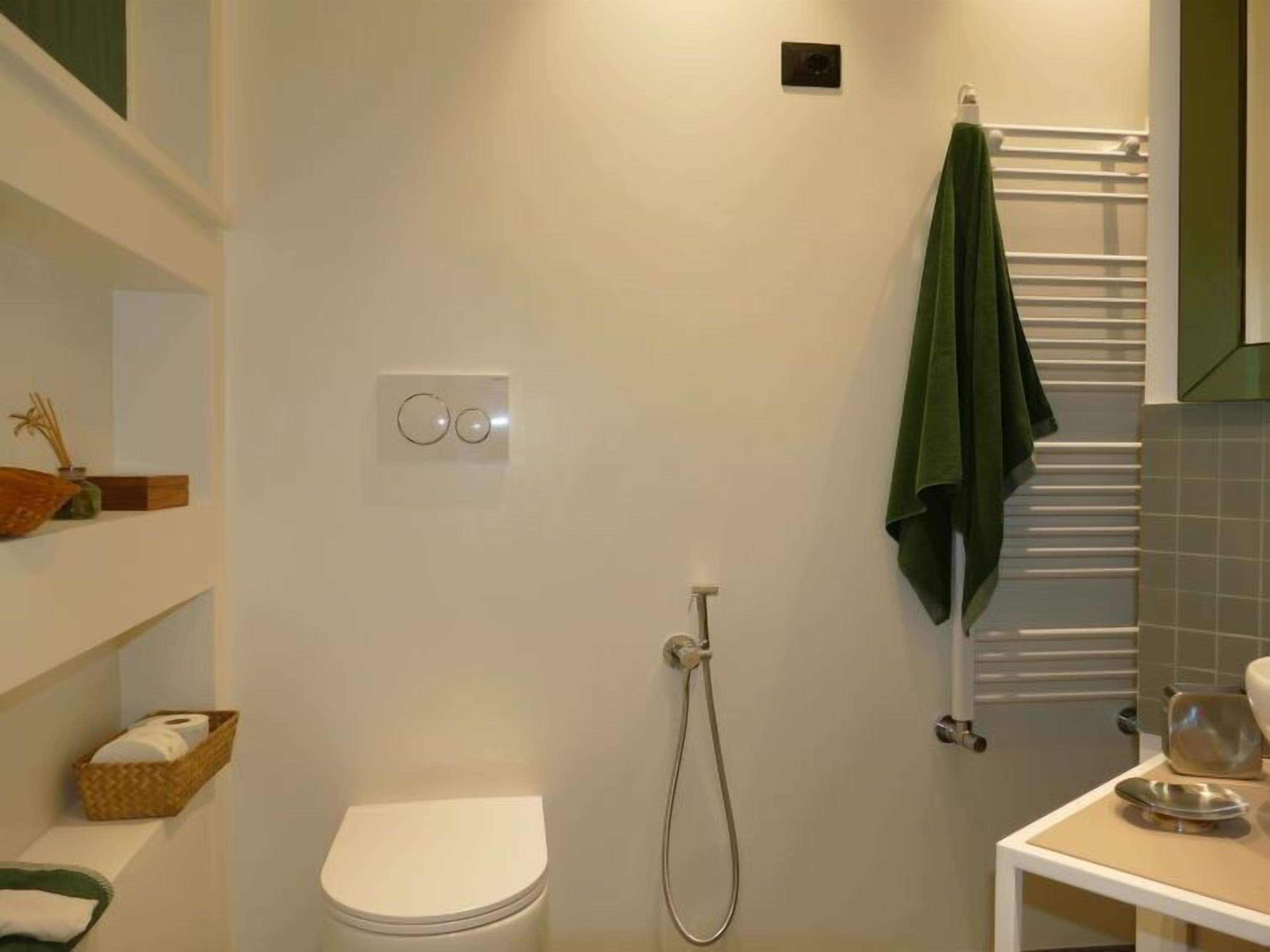 Ein Badezimmer mit Toilette, Dusche, Handtuchhalter und einem Regal mit Korb und Vase.