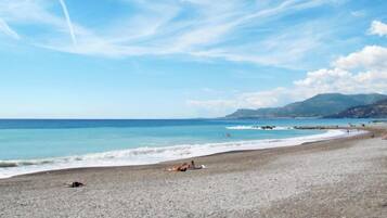 Una playa de guijarros con cielo despejado y mar en calma.