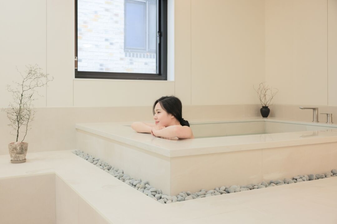A modern bathroom with a large bathtub, a window, and a potted plant.