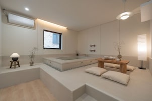 Un baño moderno con una bañera grande, una mesa de madera con teteras y un diseño minimalista.