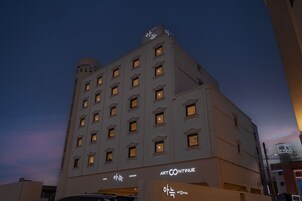 Un hotel de varios pisos con fachada plana, numerosas ventanas y un cartel que dice 'ART CONTINUE'.