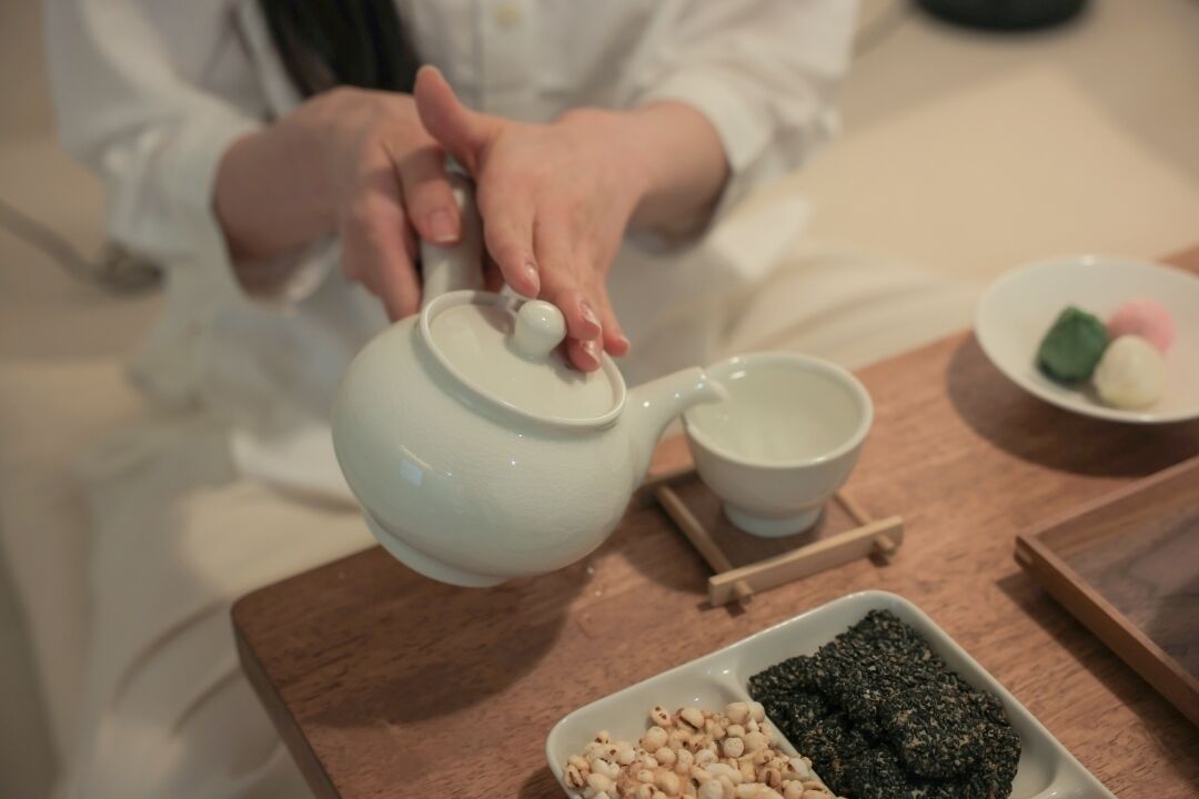 A person pouring tea from a teapot into a cup.