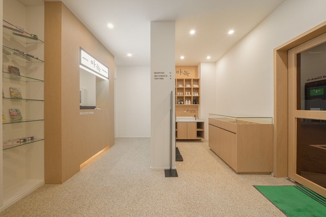 A hotel reception area with a reception desk, a self-check-in kiosk, and a reception sign.