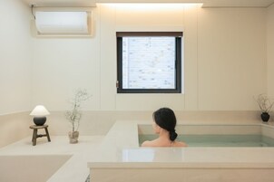 Un cuarto de spa con una bañera, una ventana con vistas, una lámpara y una planta en maceta.