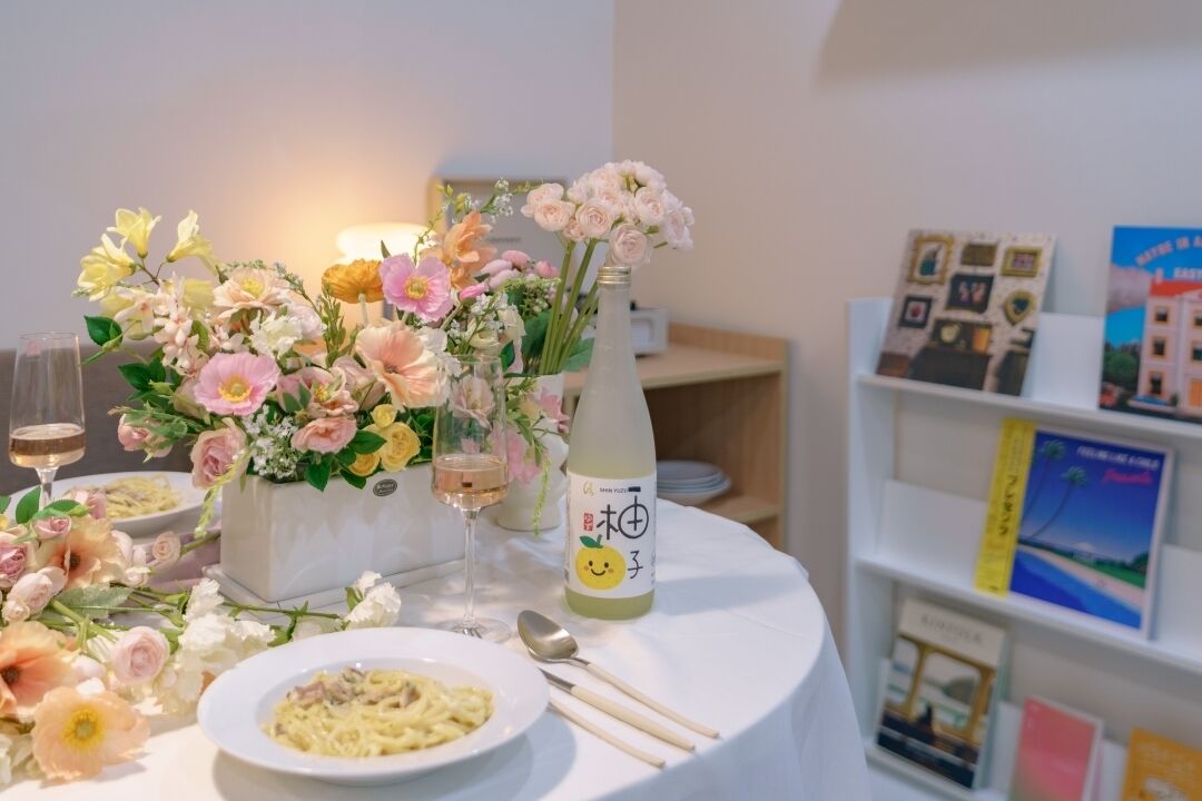 A dining table with a floral centerpiece, a bottle of drink, and a plate of food.