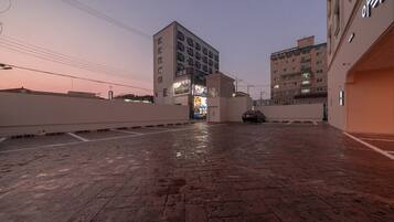 A parking area with a wet floor, surrounded by buildings with illuminated signs.