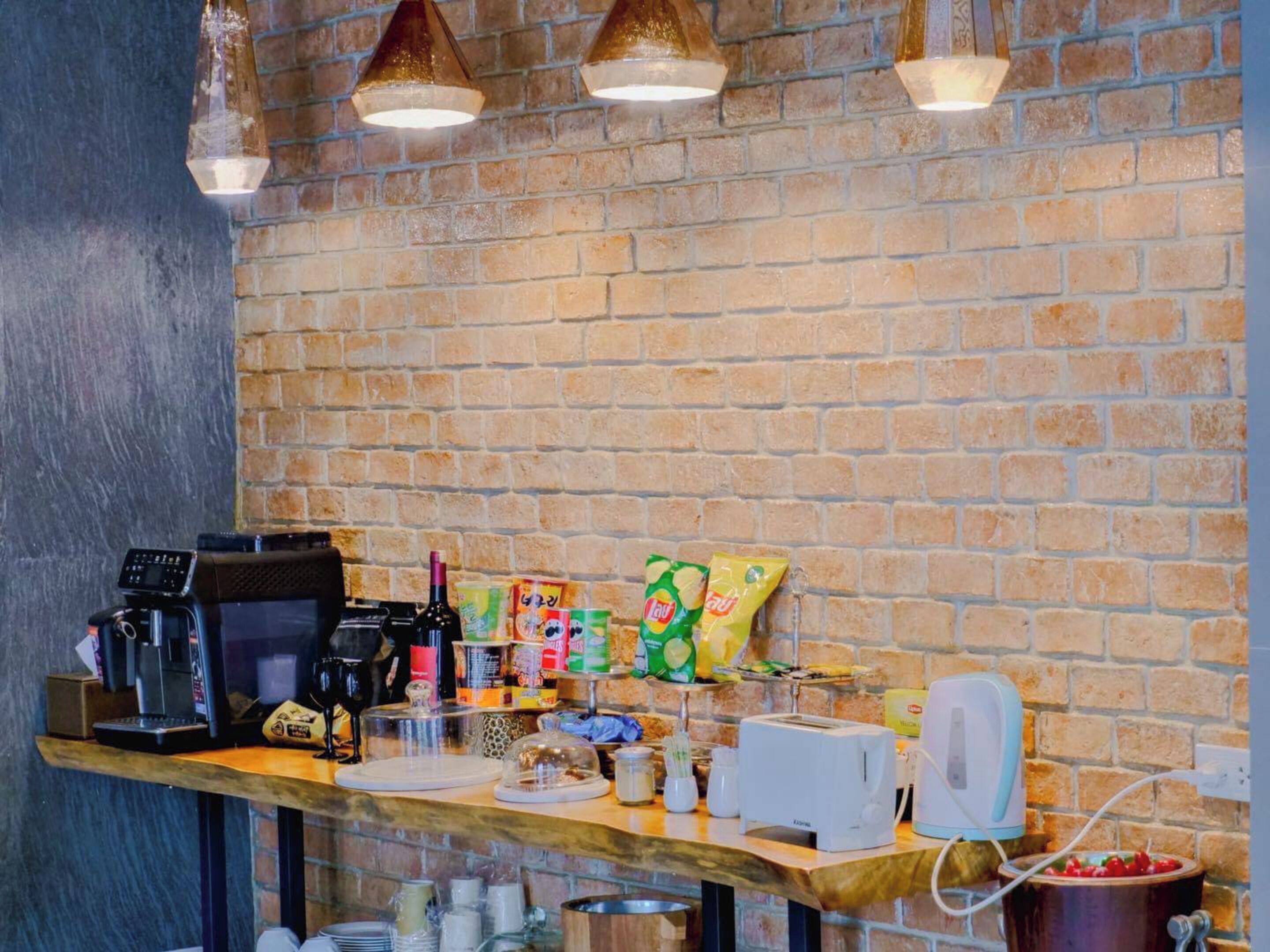 Un espace bar avec un mur en briques, une machine à café, des en-cas, un grille-pain et une bouilloire.