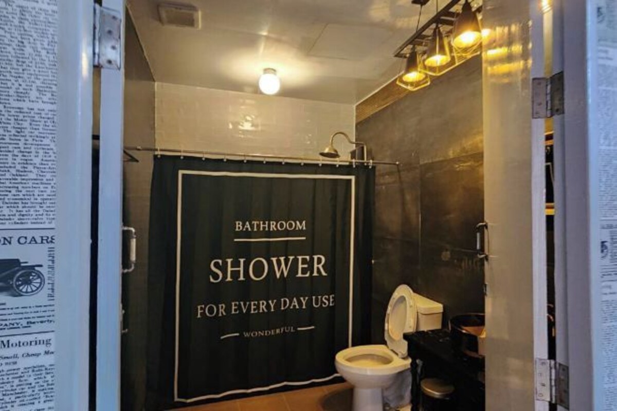 A bathroom with a shower curtain labeled "SHOWER FOR EVERY DAY USE" and a toilet.