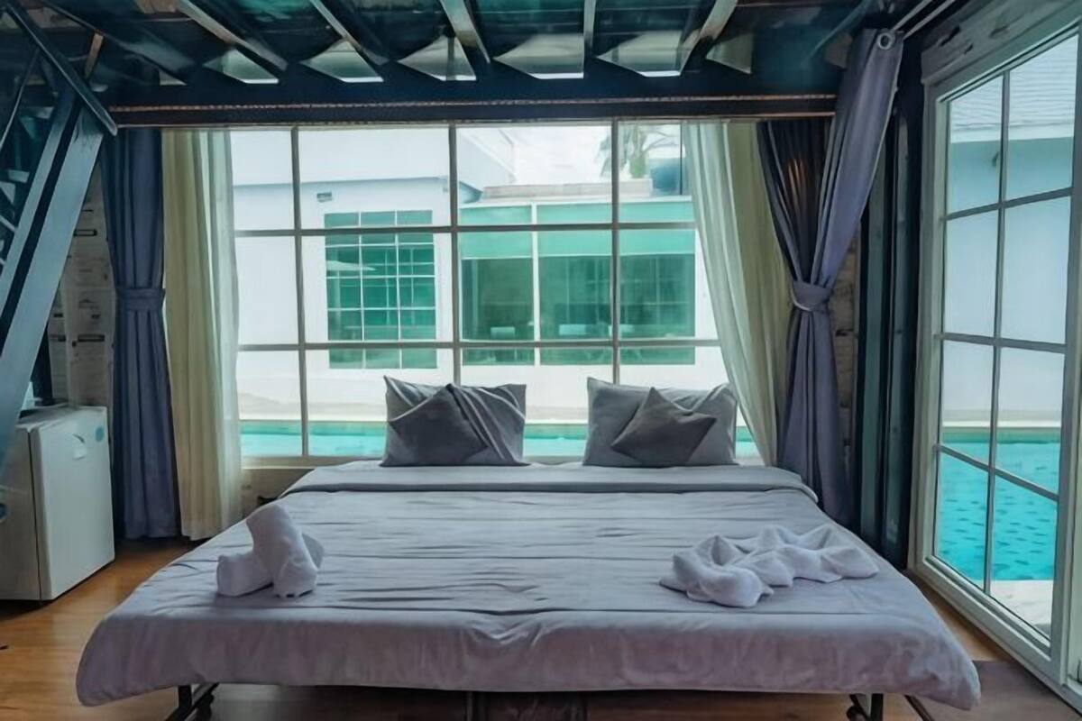 A bedroom with a bed, pillows, and a view of the sea.