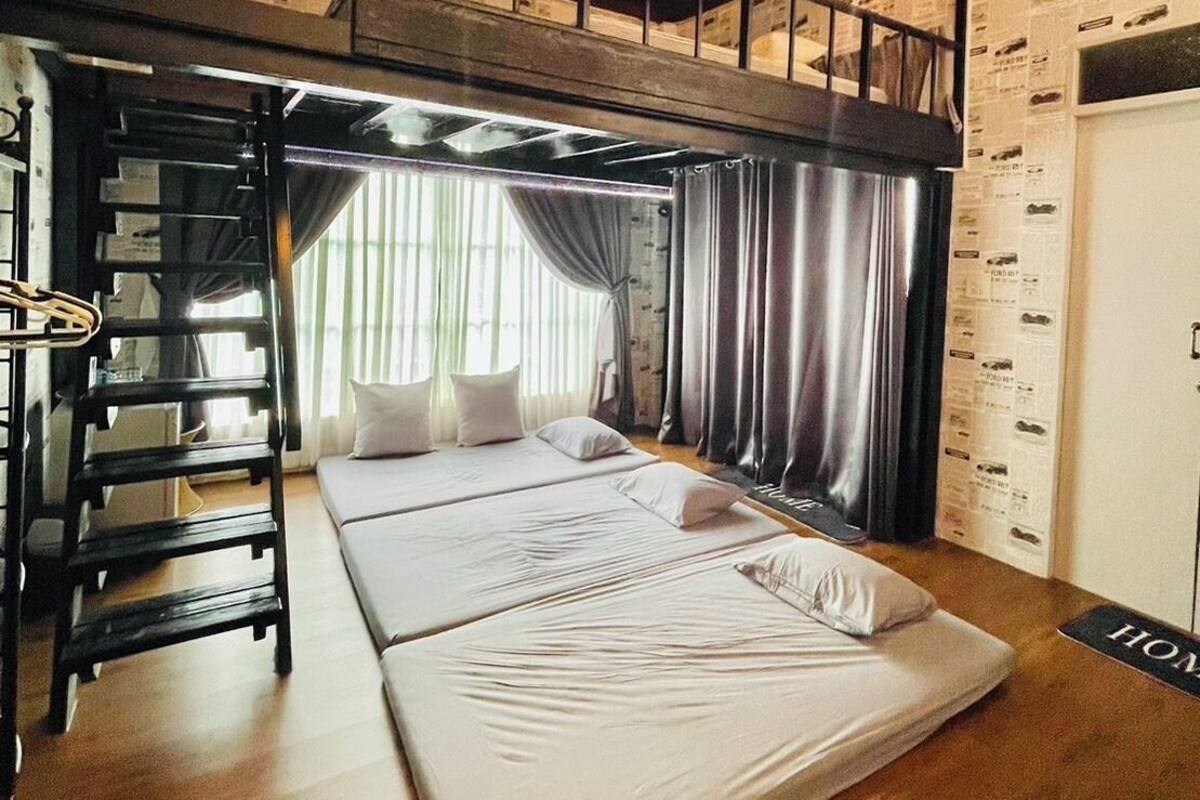 A compact room with bunk beds, a ladder, a small table, and a window with curtains.